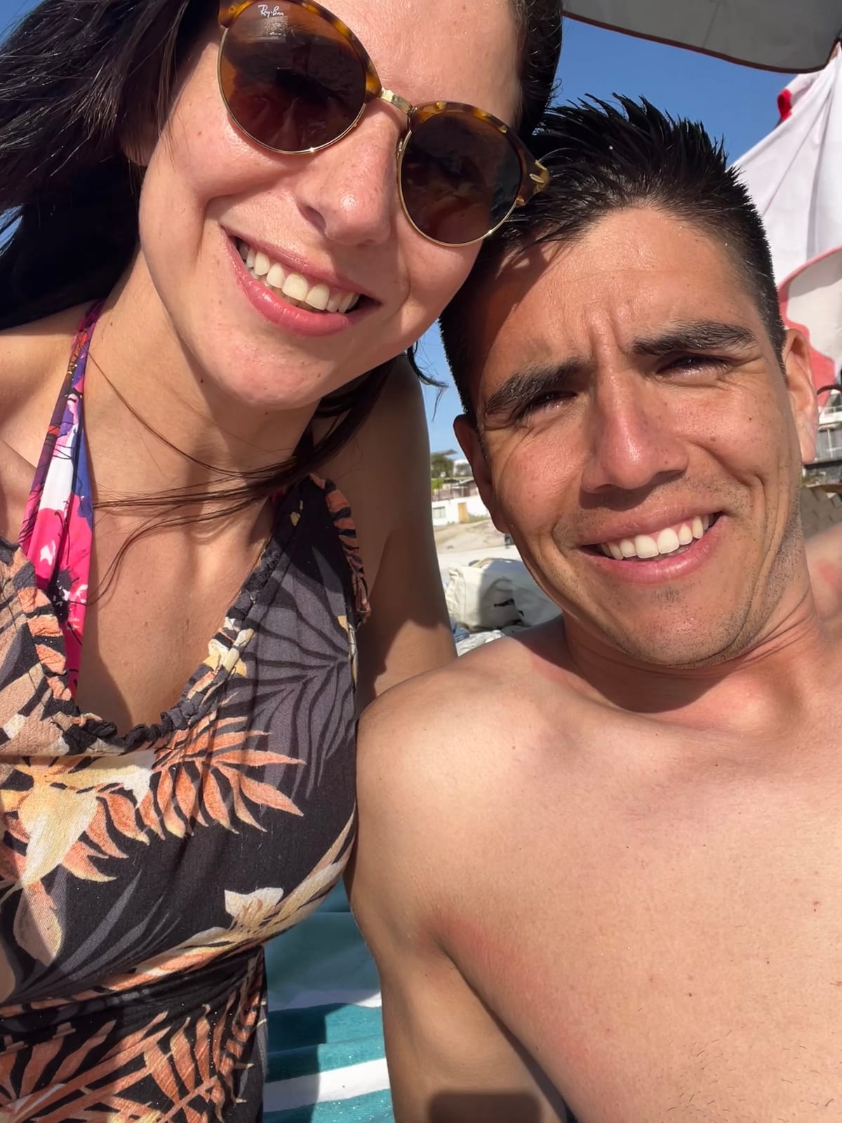 Stefy y Joaco en la playa de verano, ella con traje floreado y él sin remera