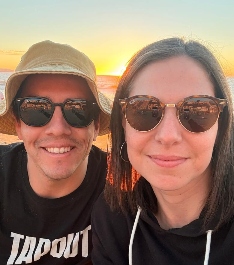 Stefy y Joaco en la playa al atardecer con anteojos de sol