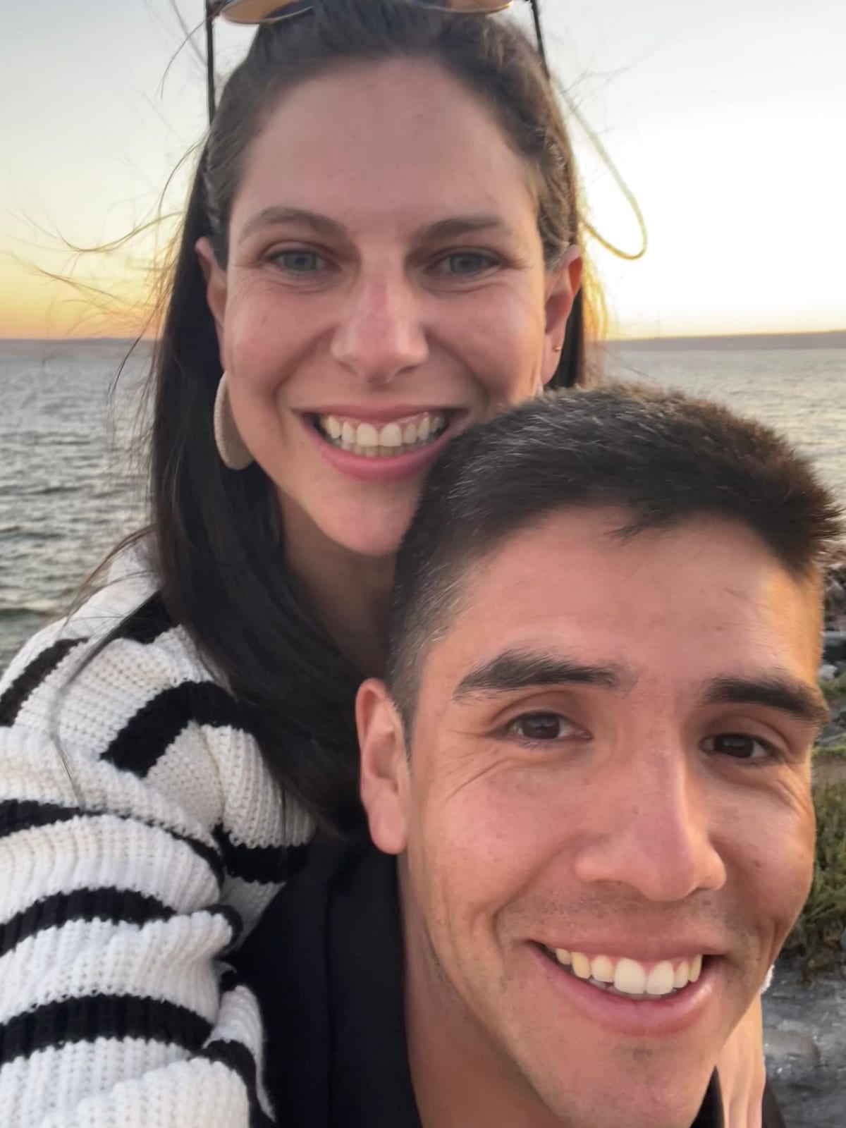 Stefy y Joaco sonriendo frente al mar al atardecer
